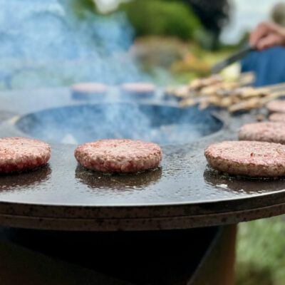 Delicious beef patties grilling on a plancha during an outdoor barbecue in Henley-on-Thames.